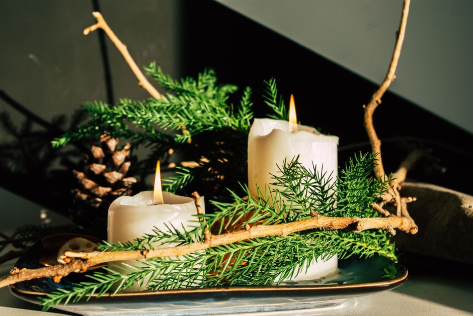 soy candle glowing on rustic wooden table with pine branches